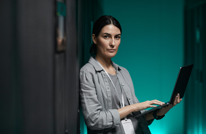 Woman standing in data center working on a laptop
